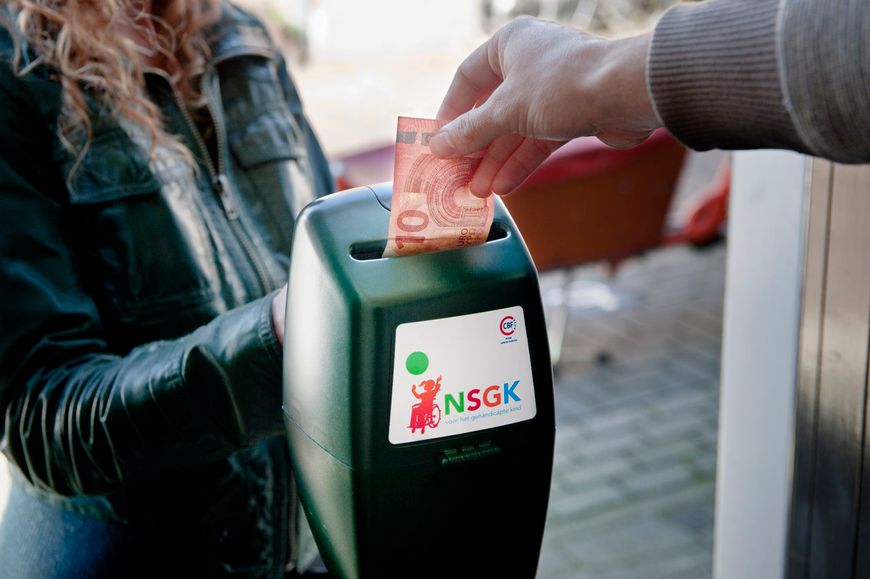 Iemand doet 10 euro in een collectebus