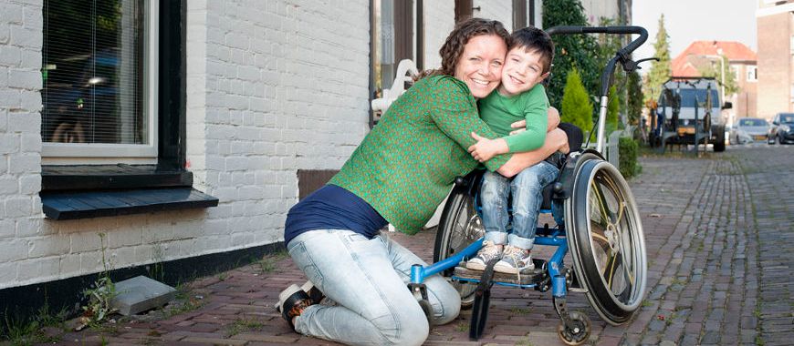 Vrouw omhelst jongen in rolstoel