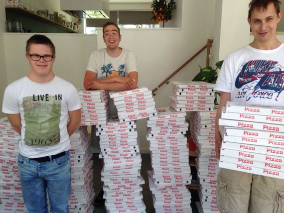 Jongeren poseren naast stapels met pizzadozen