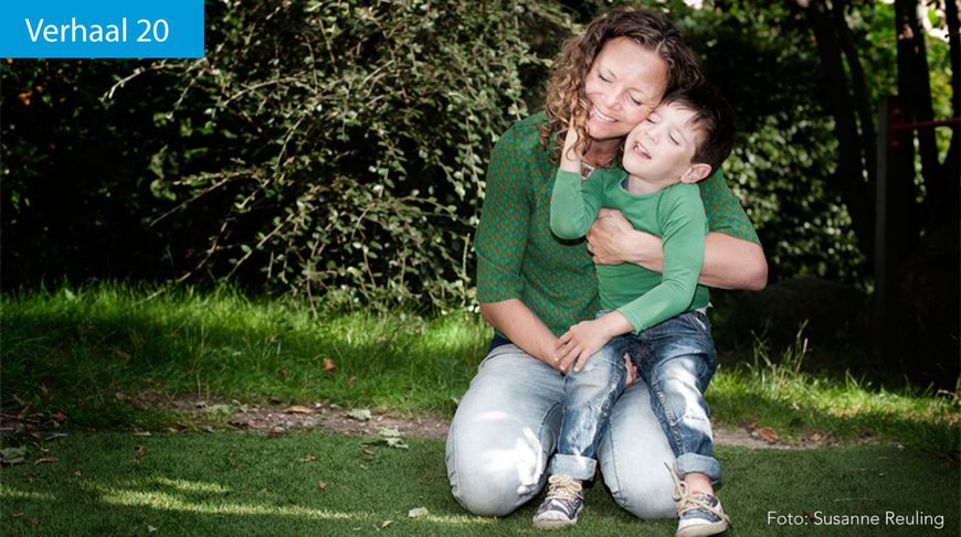 Vrouw zit met jongetje op haar schoot in het gras